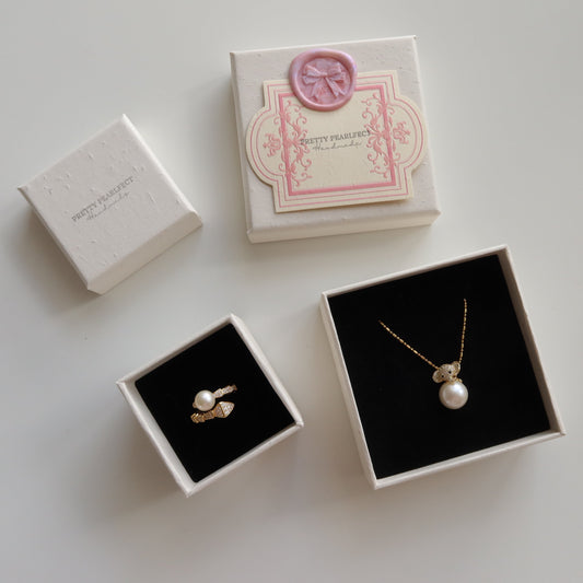 Jewelry set with pearl necklace and earrings in open boxes on a light background