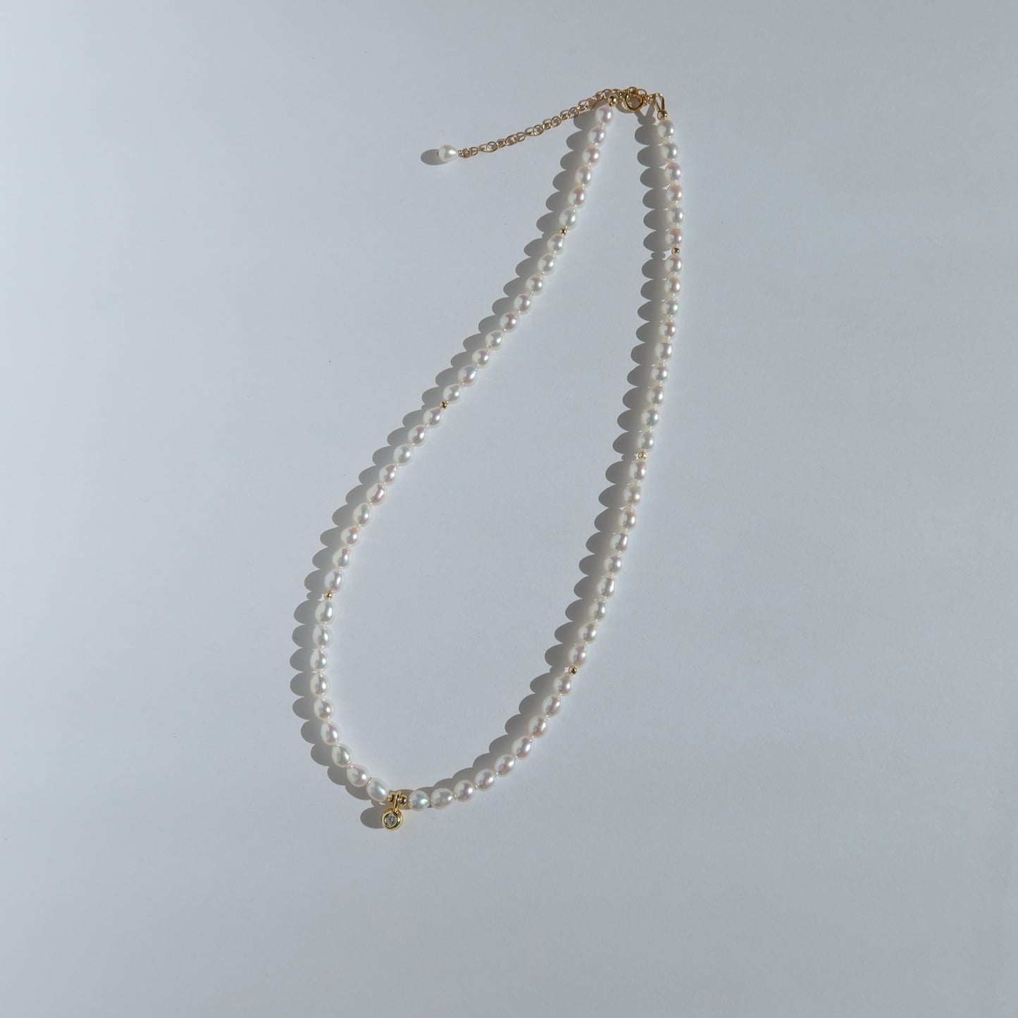 Pearl necklace with a gold clasp on a light gray background
