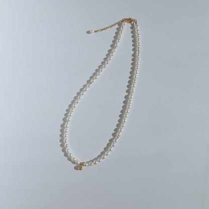Pearl necklace with a gold clasp on a light gray background