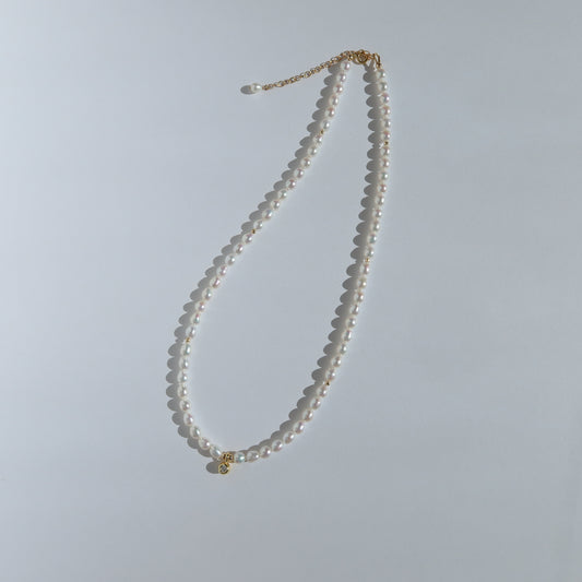 Pearl necklace with a gold clasp on a light gray background