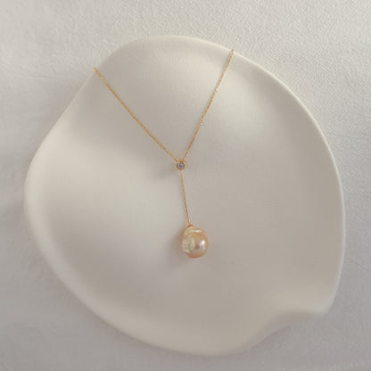 Handmade Vela Baroque Pearl Lariat Necklace laid out flat on a neutral background, highlighting the gold baroque pearl drop.