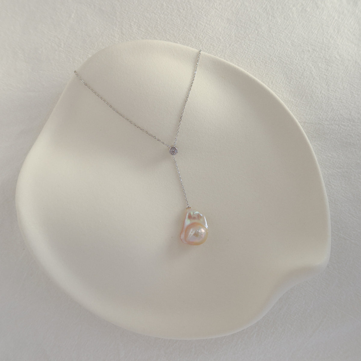 Vela Baroque Pearl Necklace showing the adjustable sliding cubic zirconia accent and organic freshwater baroque pearl on a silver chain.