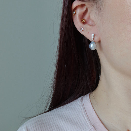Close-up of a person wearing the Adeline Blue Akoya Baroque Pearl Earrings, highlighting their iridescent blue akoya baroque pearl and sparkling pavé stone setting.