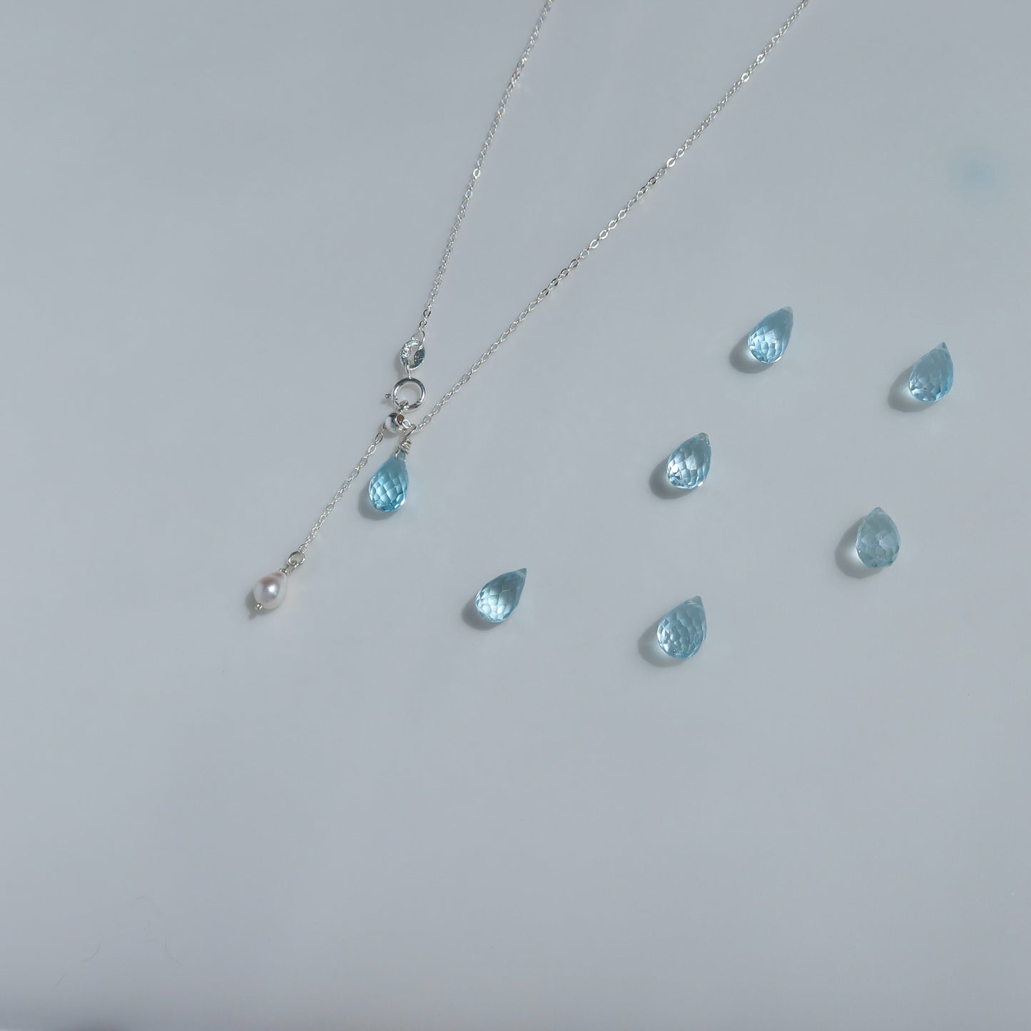 Necklace with blue teardrop topaz pendants on a light gray background