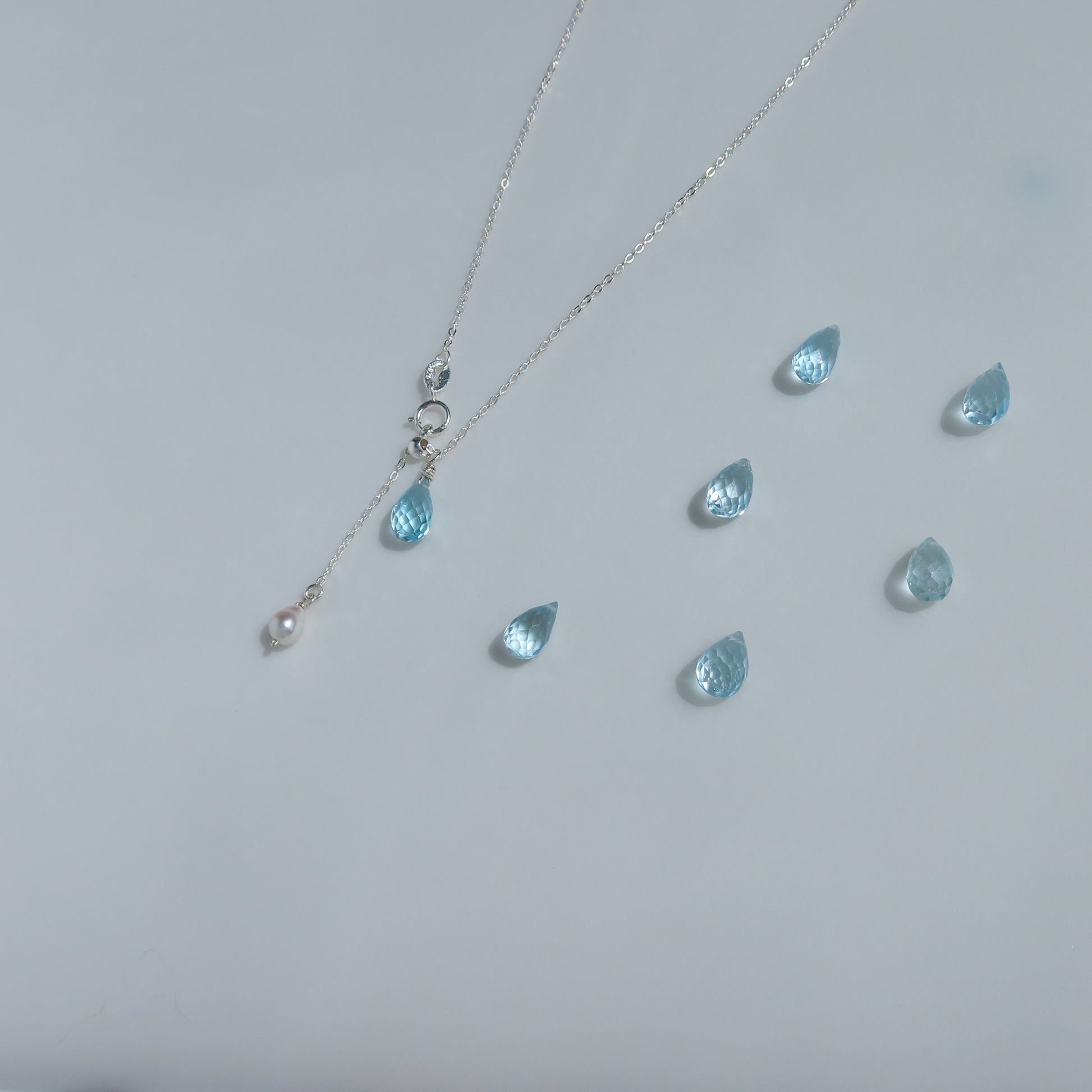 Necklace with blue teardrop topaz pendants on a light gray background