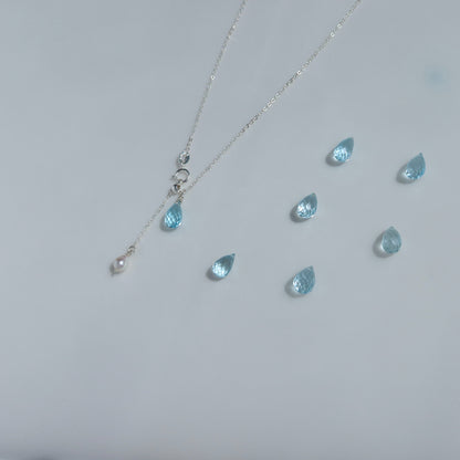 Necklace with blue teardrop topaz pendants on a light gray background