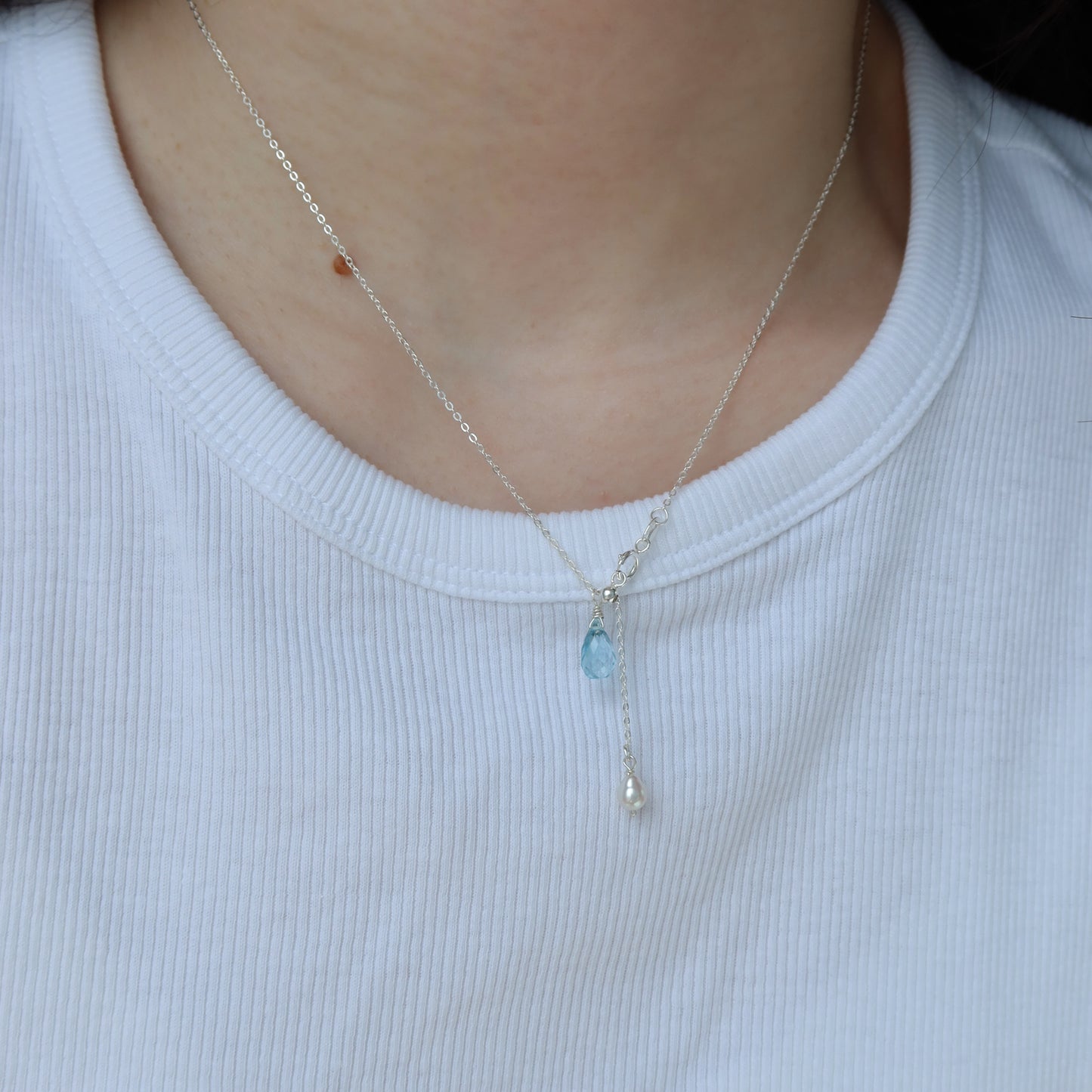 Necklace with a pendant worn by a person on a white shirt