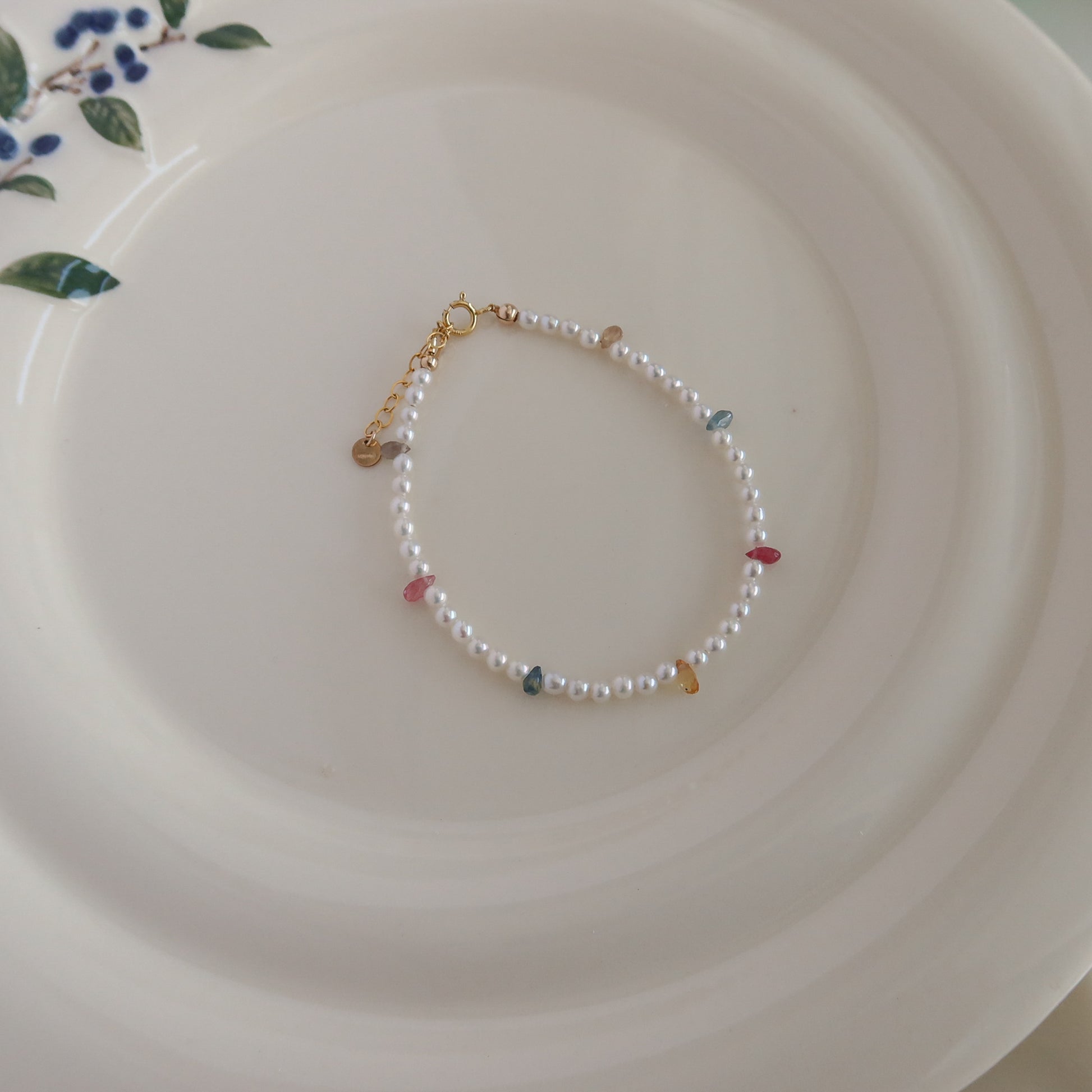 Pearl bracelet with small sapphire beads on a white plate