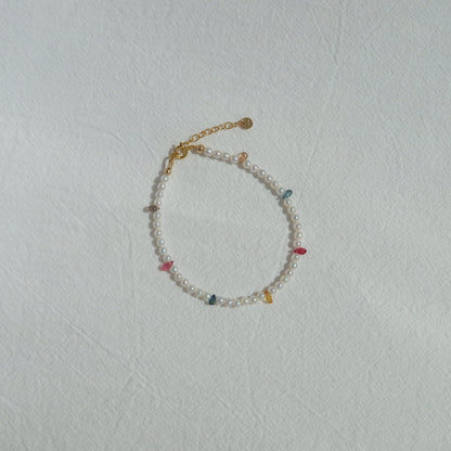 Pearl bracelet withrainbow sapphire beads on a light gray background