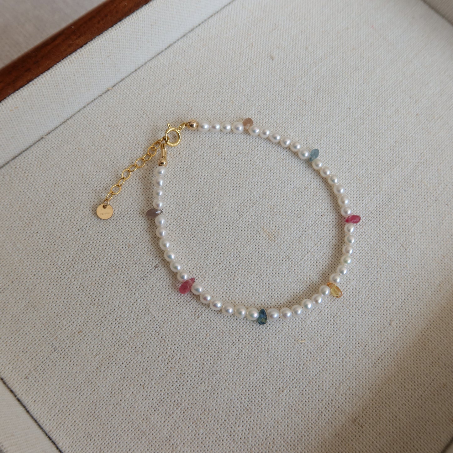 Pearl bracelet with colorful sapphire beads on a neutral background