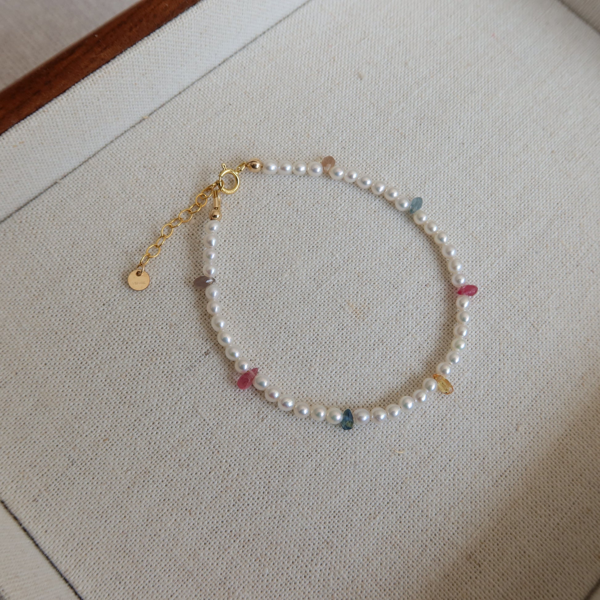 Pearl bracelet with colorful sapphire beads on a neutral background