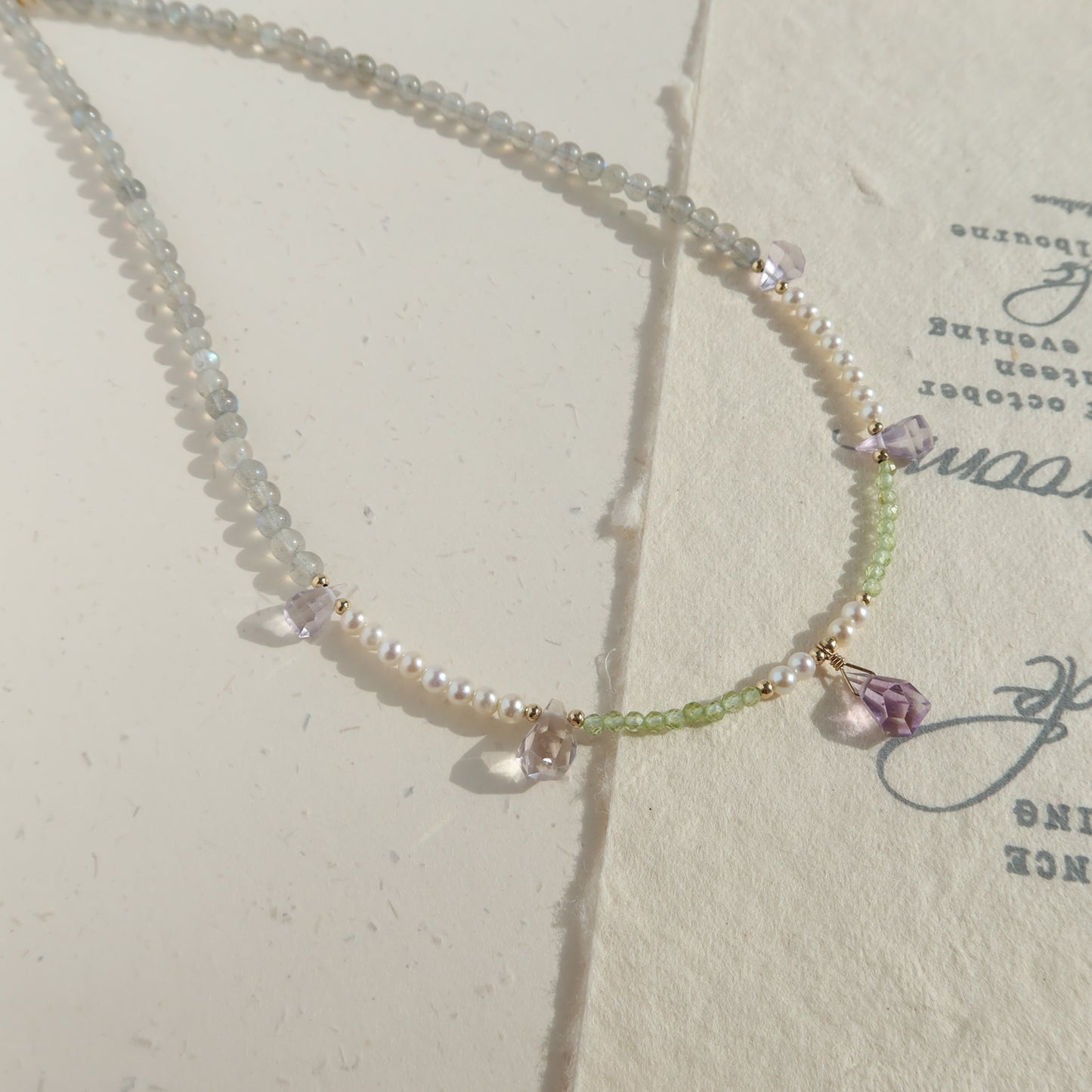 Necklace with moonstone, pearl and ametrine on a textured surface