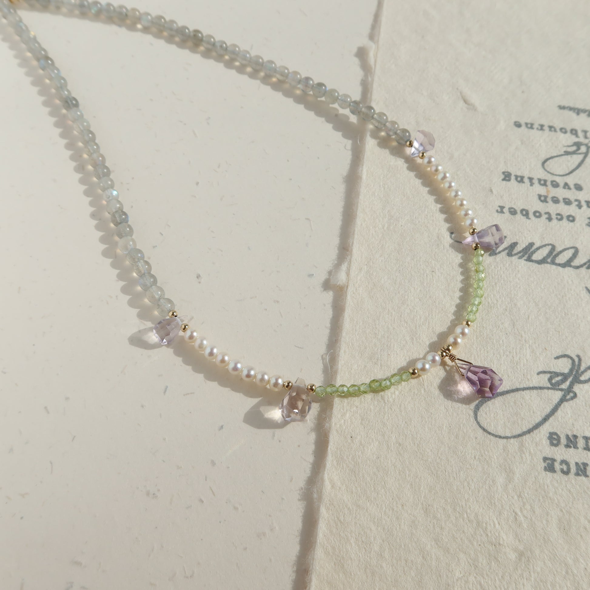 Necklace with moonstone, pearl and ametrine on a textured surface
