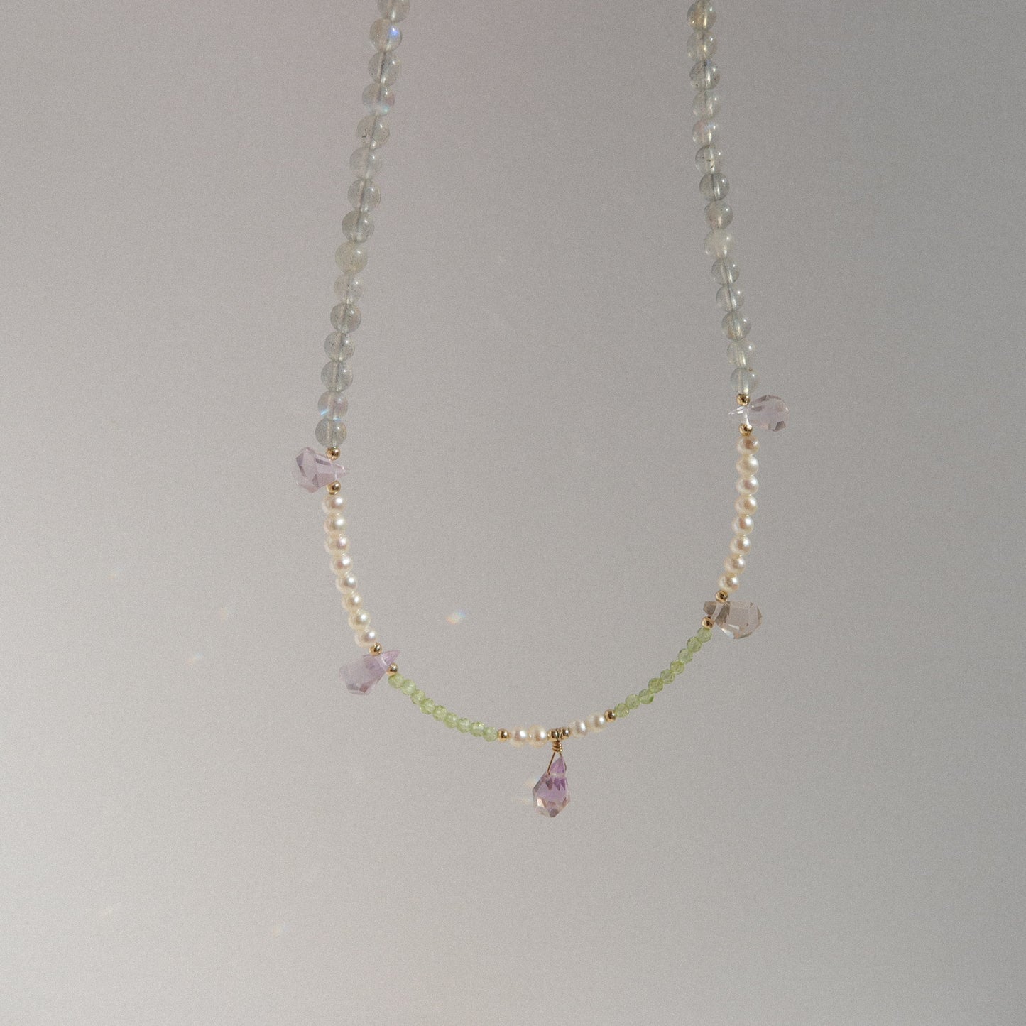 Delicate necklace with smoonstone, freshwater pearls and teardrop ametrine pendant on a gray background