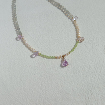 Necklace with pearls, moonstone and ametrine stones on a light gray background