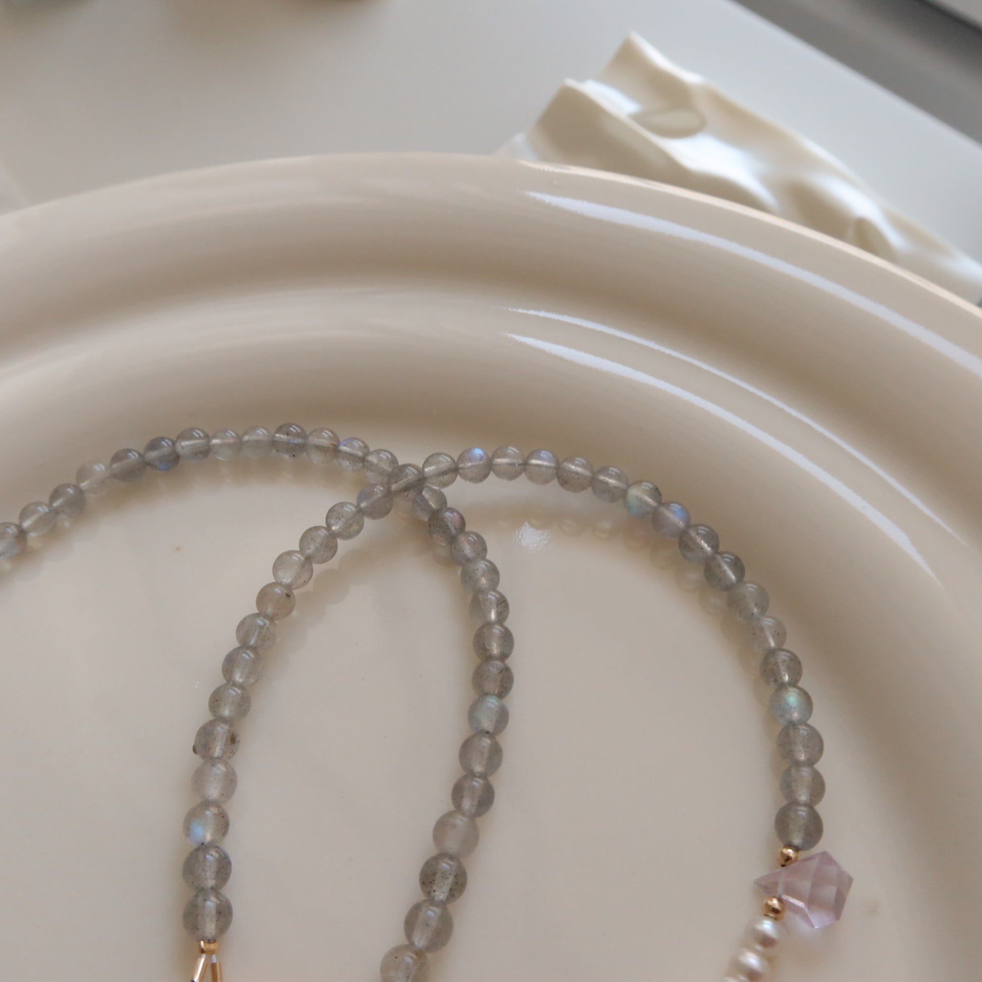 Beaded moonstone necklace on a white ceramic plate