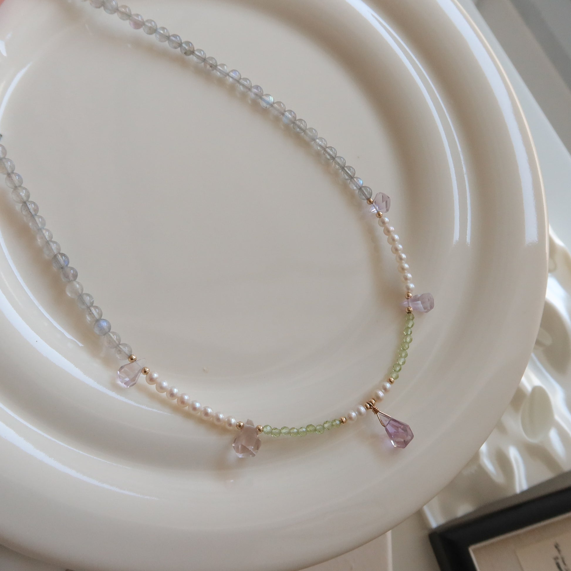 Necklace with moonstone, freshwater pearls and ametrine stones on a white plate