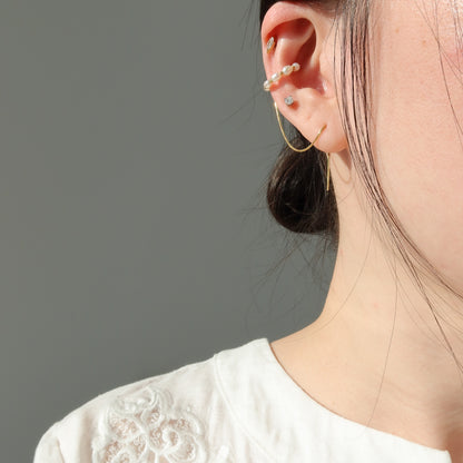 Close-up of a person wearing gold pearl ear cuff with a neutral background
