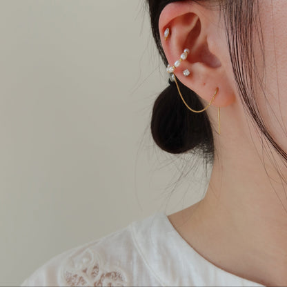 Close-up of an ear with pearl earrings against a neutral background