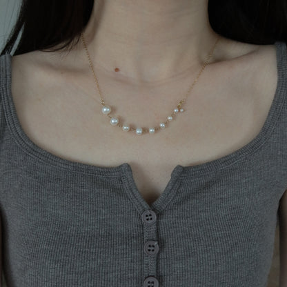 Pearl necklace worn by a person in a gray top
