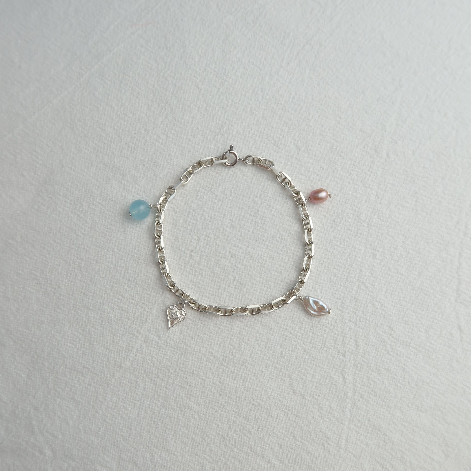 Silver bracelet with charms on a light gray background