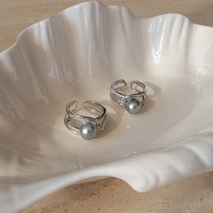 Two Sirene Tahitian Pearl Rings resting inside a white ceramic shell dish, showcasing their 8.7mm platinum-gray Tahitian pearls and twisted pavé silver bands.