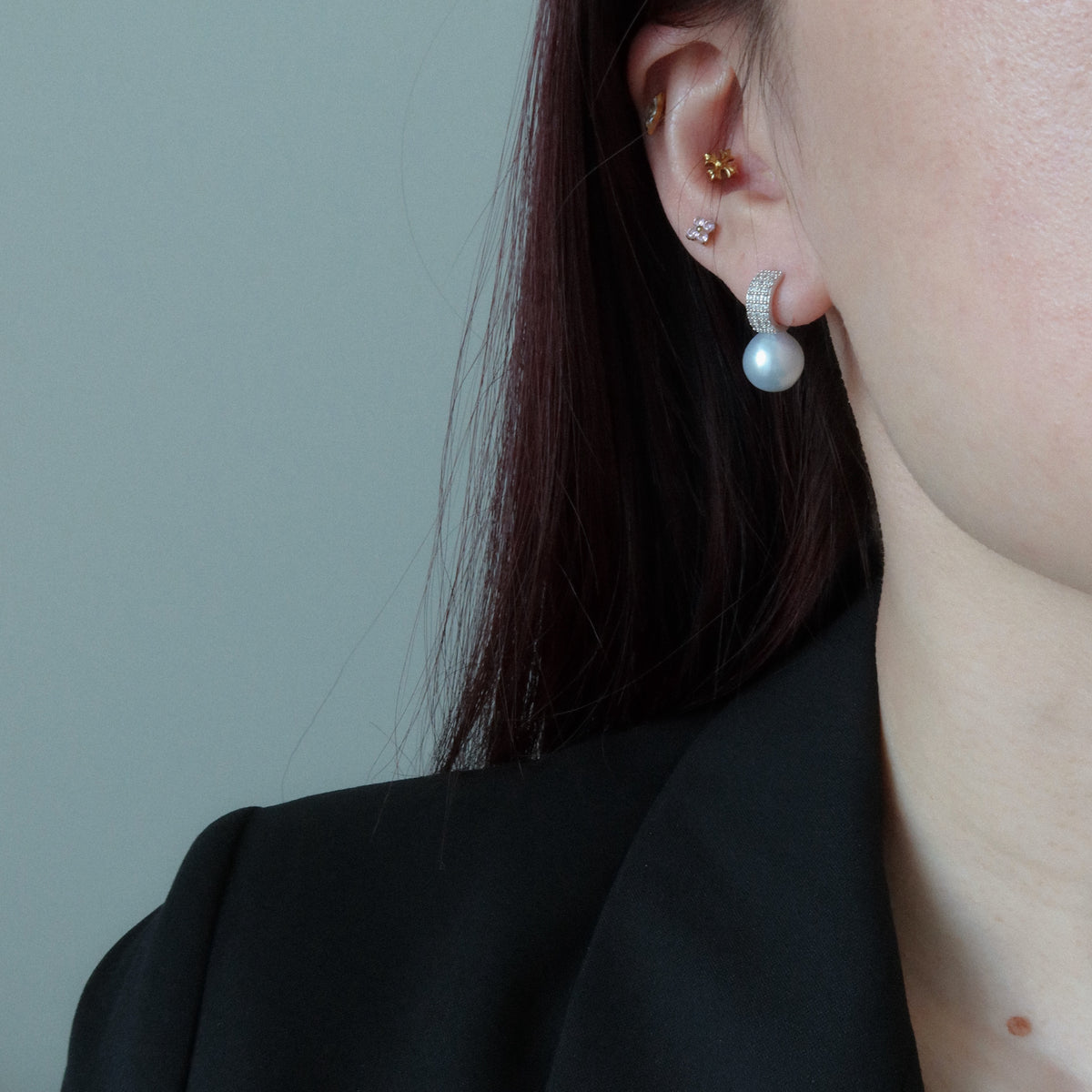 Model wearing the Nova South Sea Baroque Pearl Earrings, featuring a large blue-toned white baroque pearl suspended from a pavé huggie hoop.