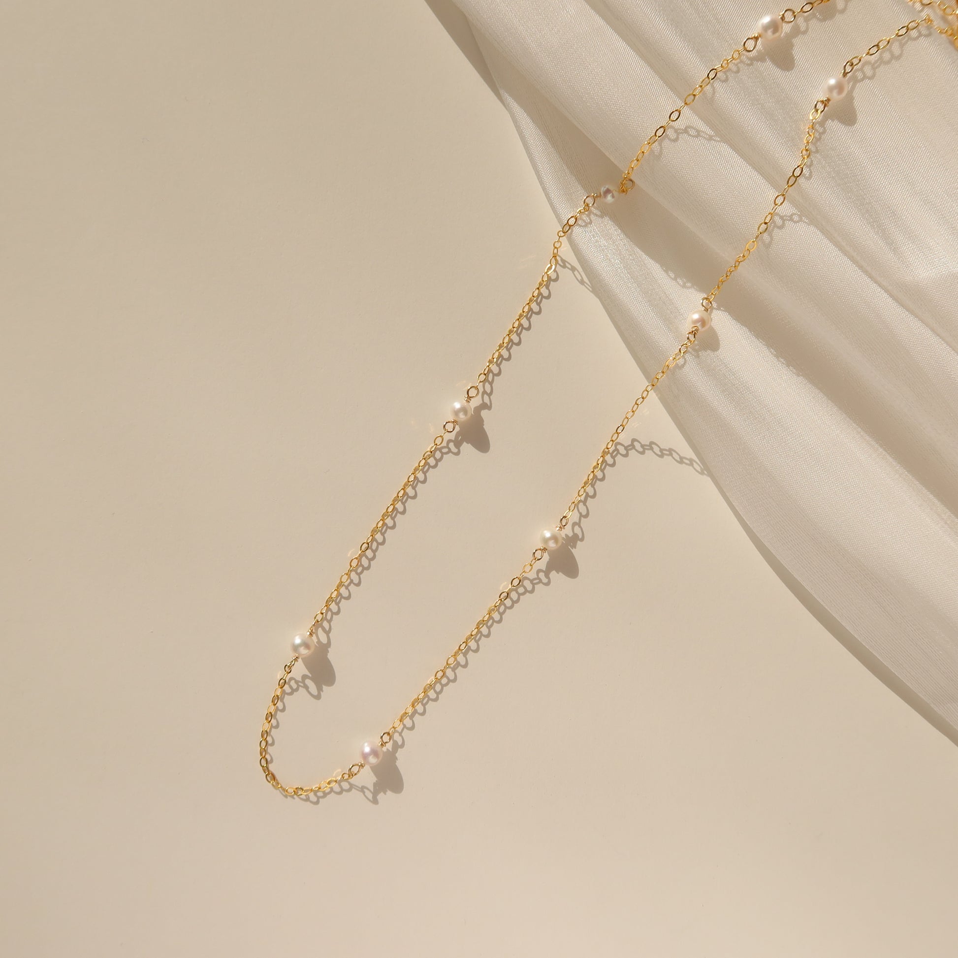 A dainty choker necklace featuring freshwater pearls on a gold-filled chain, displayed on a neutral background.