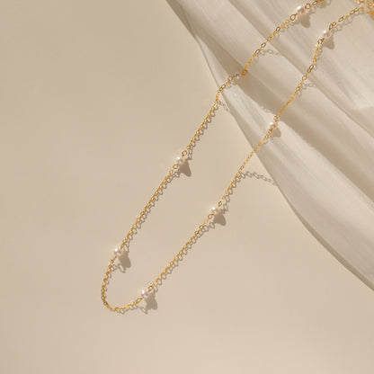 A dainty choker necklace featuring freshwater pearls on a gold-filled chain, displayed on a neutral background.